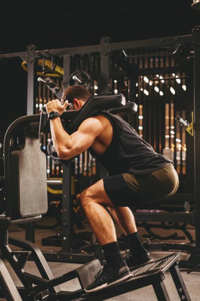 Home athletic man doing legs exercise on squat machine at the gym